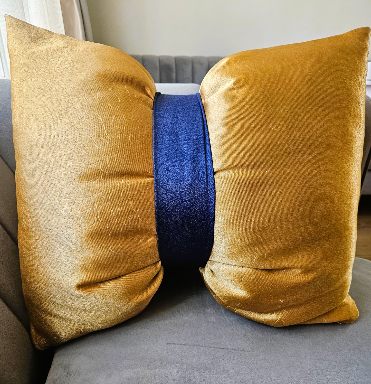 Gold pillow with a blue center cushion on a sofa.