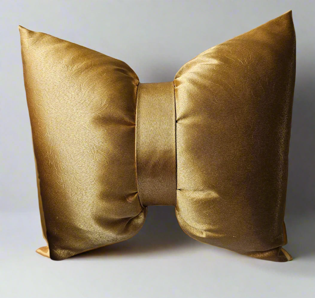 Gold bow-shaped pillow on a white sofa