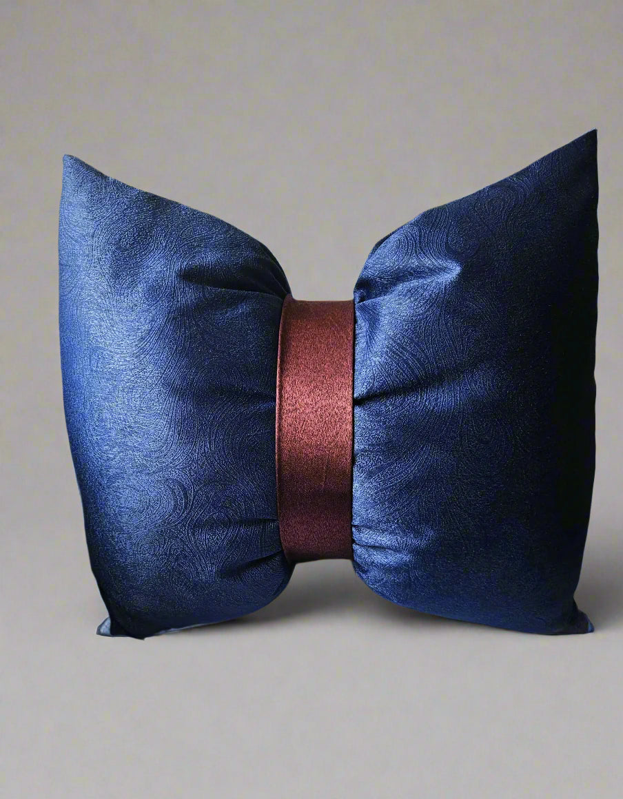Navy blue decorative pillow with a maroon center on a beige sofa.