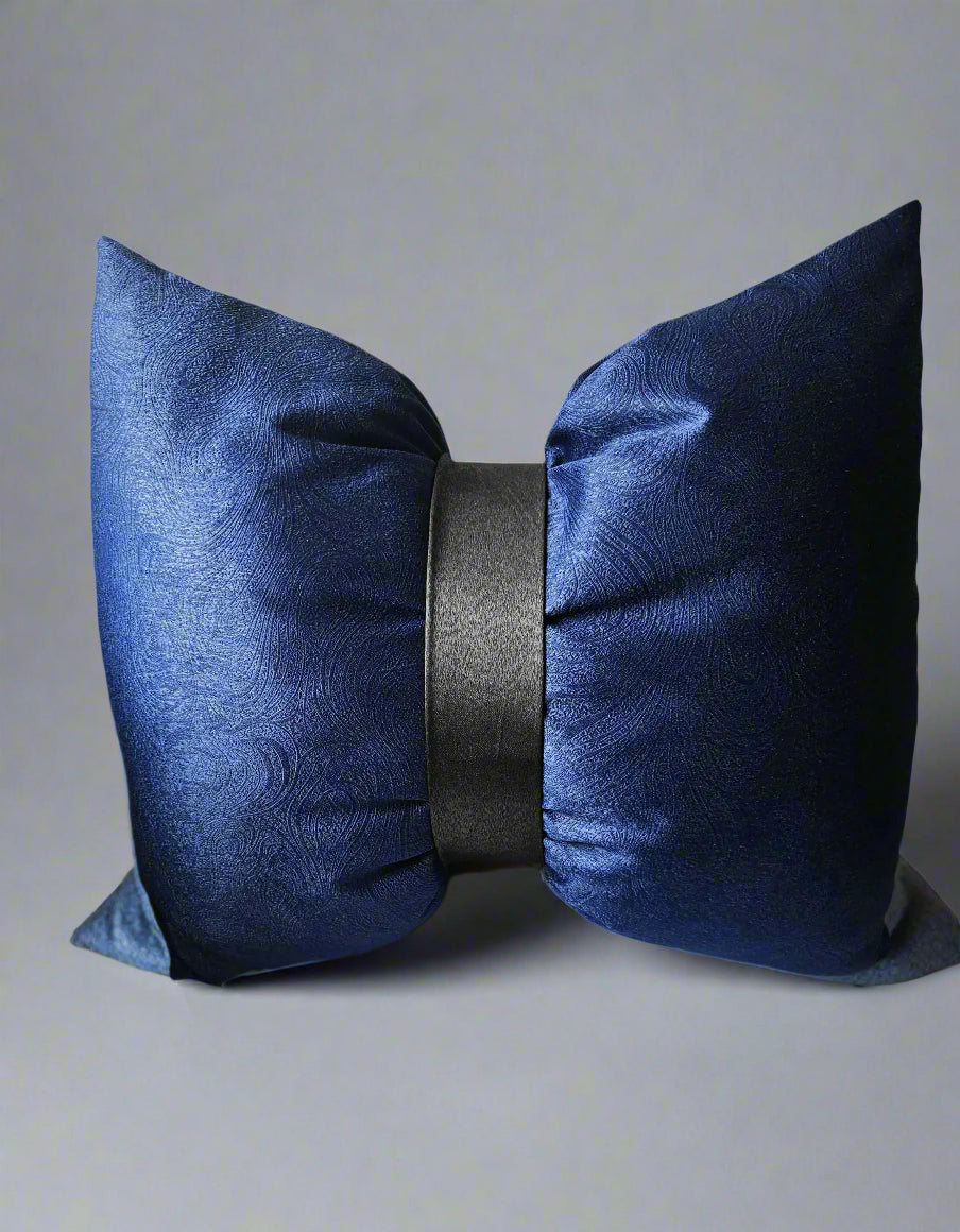 Navy blue decorative pillow with a black center on a beige sofa.