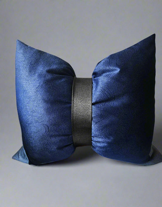 Navy blue decorative pillow with a black center on a beige sofa.