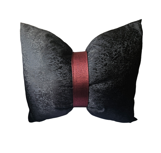 Black textured pillow with a red ribbon on a white background