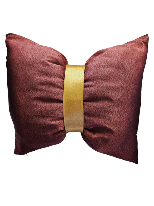 Bow-shaped pillow with a gold band on a white background